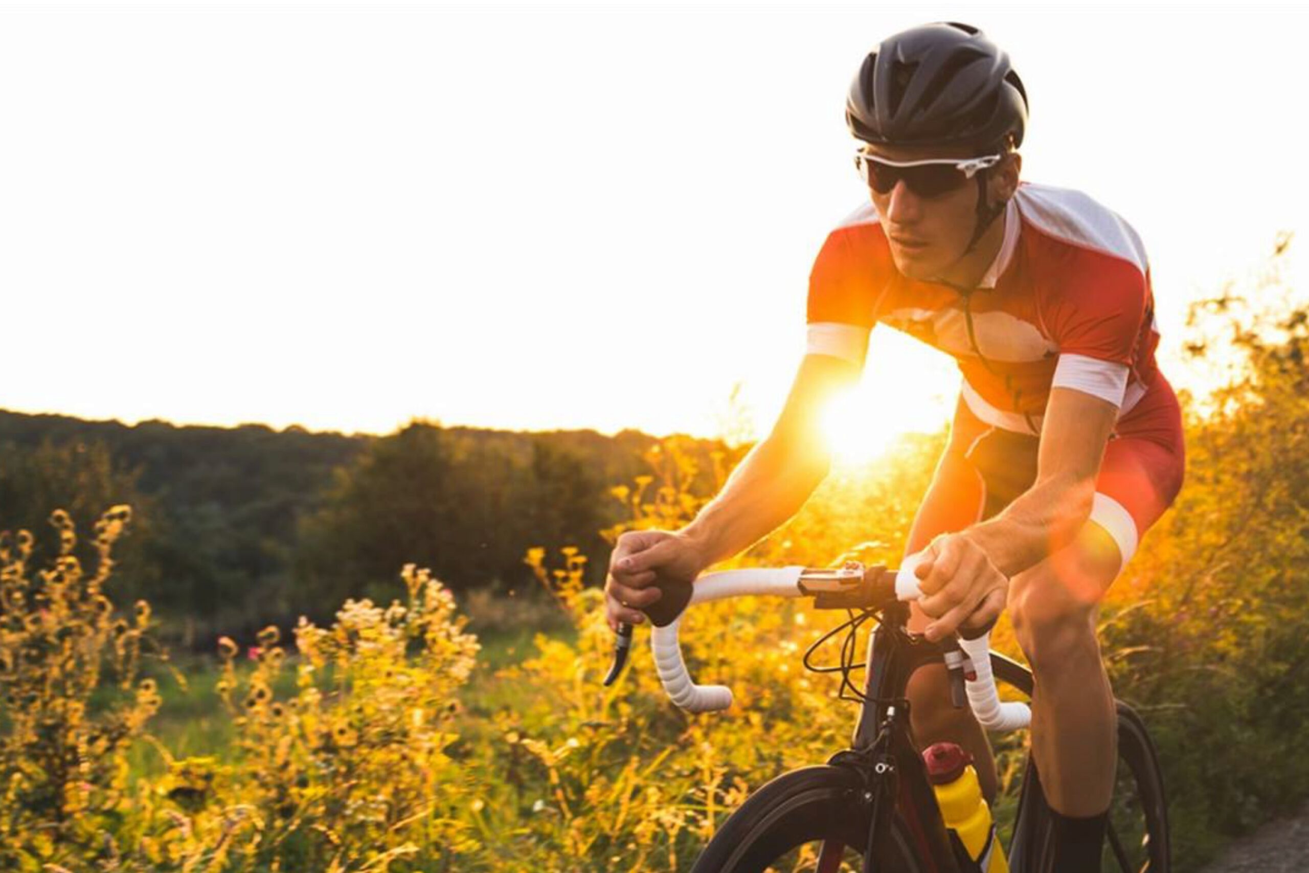 Cyclist riding on a scenic countryside road at sunset, outdoor cycling fitness and endurance training.