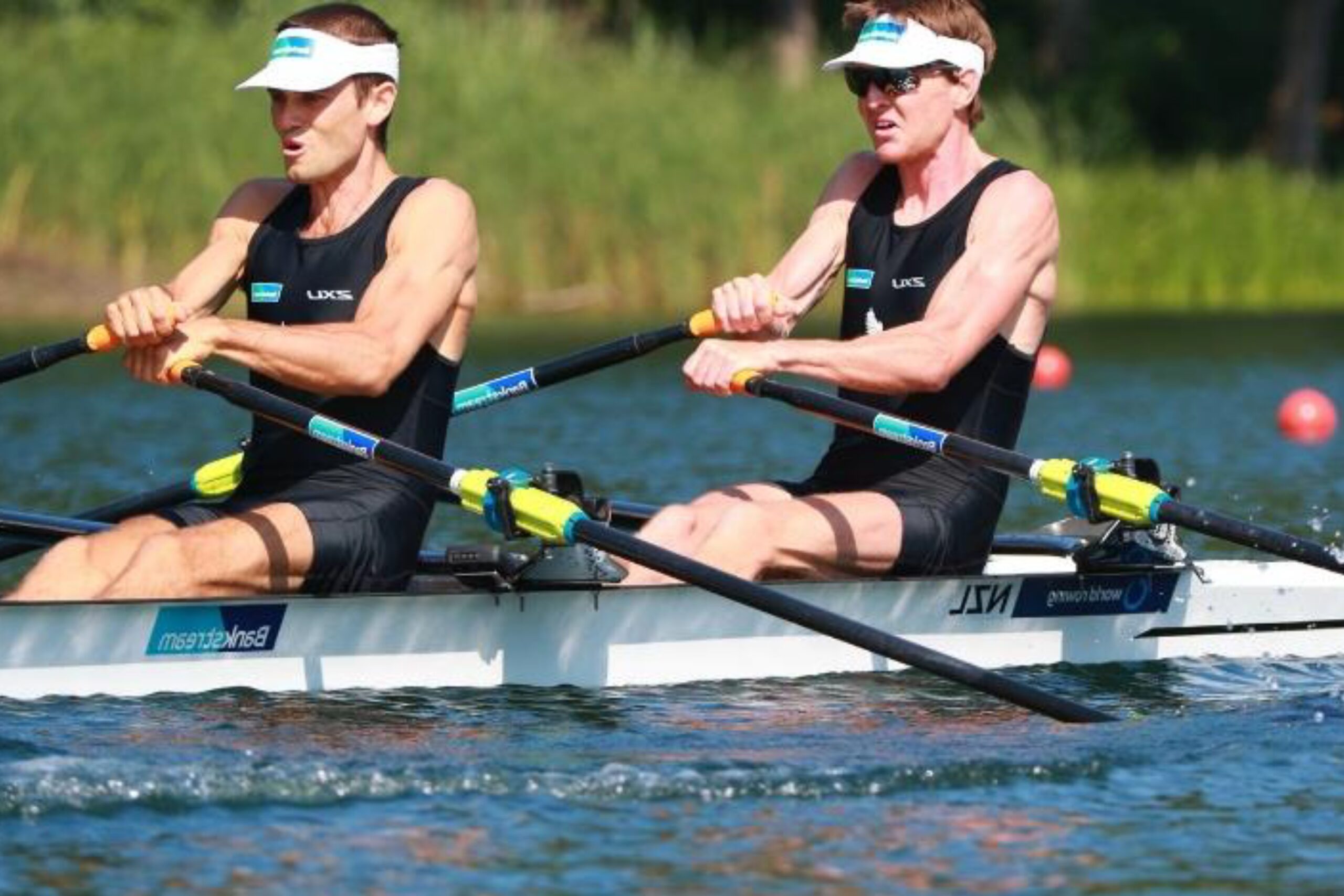Two athletes rowing a racing boat on a calm river, competitive rowing and team water sport training.